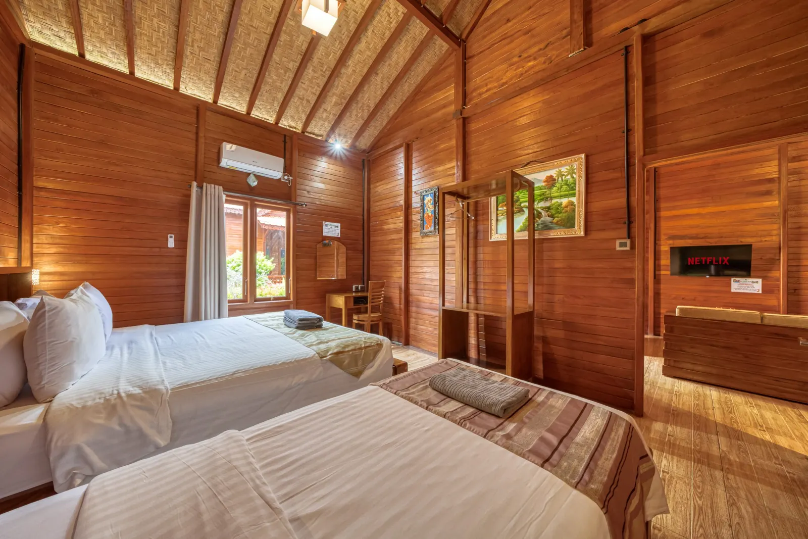Double bed beneath exposed timber beams in a wooden bedroom