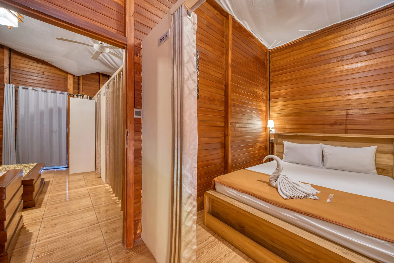 Single bed beside curtains in a timber-paneled room