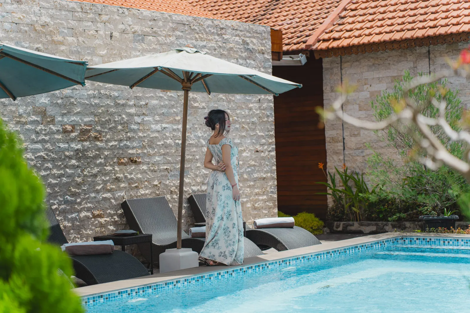 Guest beside poolside loungers under a sun umbrella